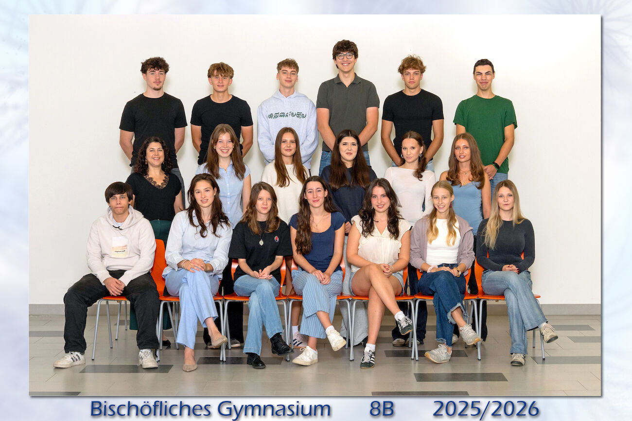 Eine Schulklasse und ihr Lehrer stellen sich für ein Gruppenfoto in einer Schule auf.