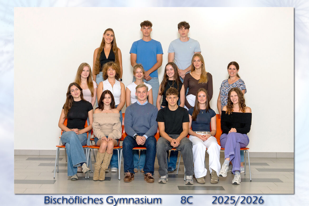 Eine Gruppe von Schülern und eine Lehrerin posieren für ein Klassenfoto im Haus.