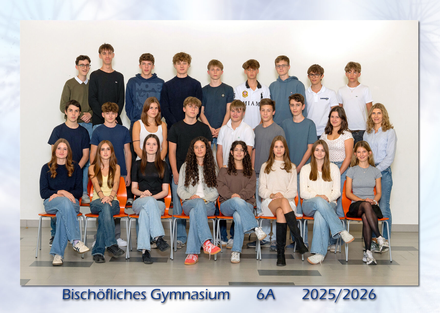 Eine Schulklasse und ihr Lehrer stellen sich für ein Gruppenfoto in der Schule auf.