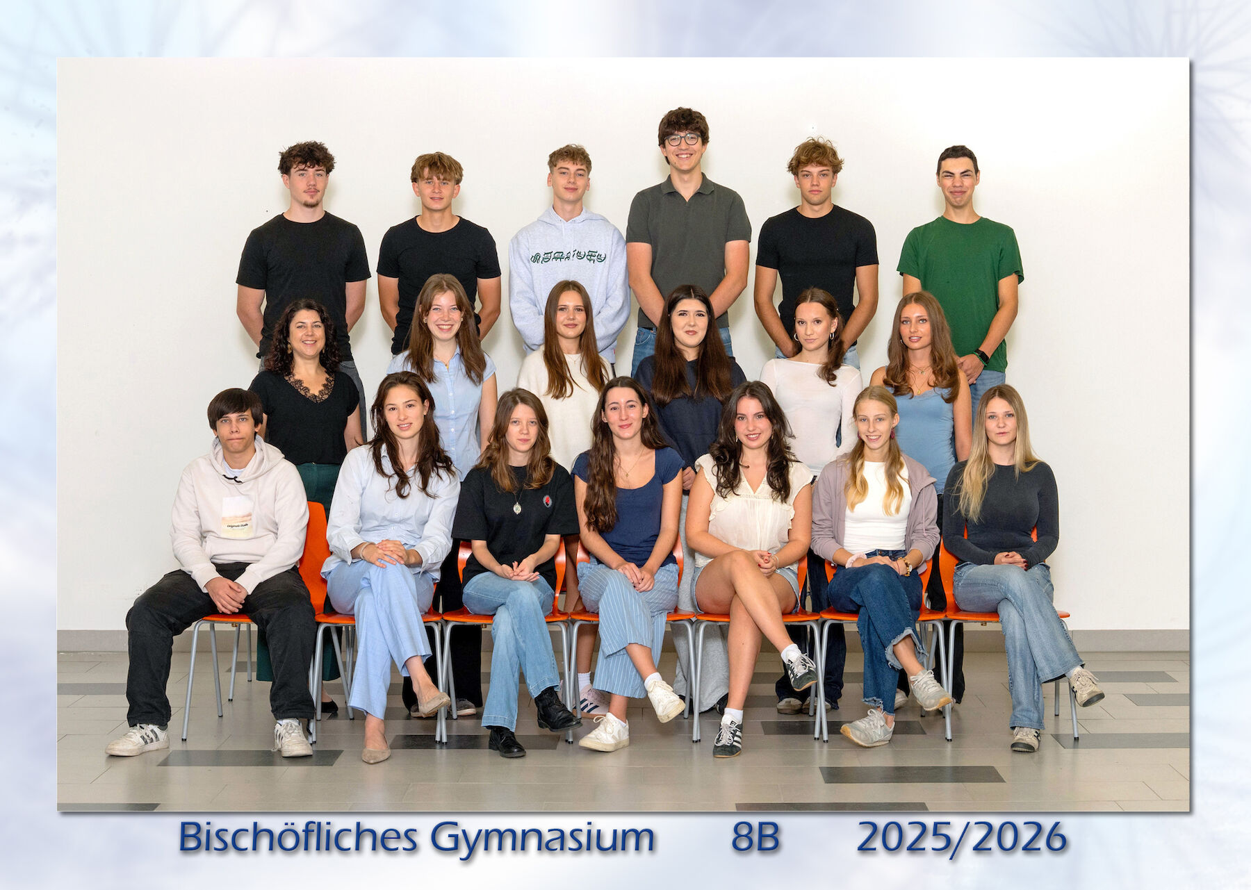 Gruppenfoto von Schülern und einem Lehrer, sitzend und stehend, die in die Kamera lächeln.