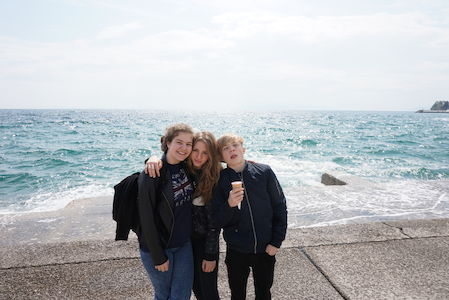 Drei Freunde stehen am Meer und machen ein Selfie an einem sonnigen Tag.