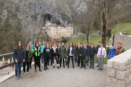 Eine Gruppe von Menschen posiert vor einer in einen felsigen Hügel gebauten Burg.