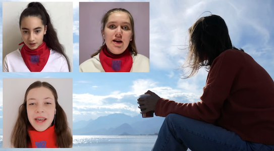 Drei Mädchen mit roten Tüchern und eine Frau, die am Wasser sitzt und die Berge im Rücken hat.