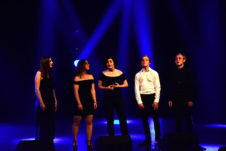 Fünf Personen singen auf der Bühne unter blauen Scheinwerfern.