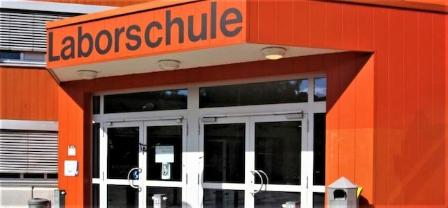 Eingang eines Gebäudes mit Laborschule-Schild über Glastüren.