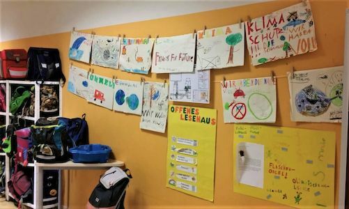 Zeichnungen und Poster von Kindern zum Thema Klimawandel an der Wand eines Klassenzimmers.