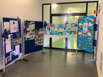 Aushang im Schulflur mit Erasmus+ Postern, Fotos und kleinen EU-Flaggen.