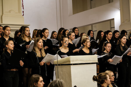 Ein Frauenchor, der in einer Kirche singt und Notenblätter hält.