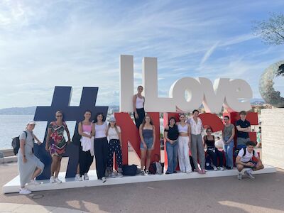 Eine Gruppe posiert vor einem großen I Love Nice-Schild an der Küste.