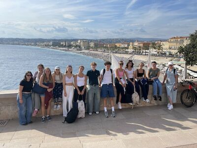 Eine Gruppe von Jugendlichen posiert an einem sonnigen Tag an einer Strandpromenade.