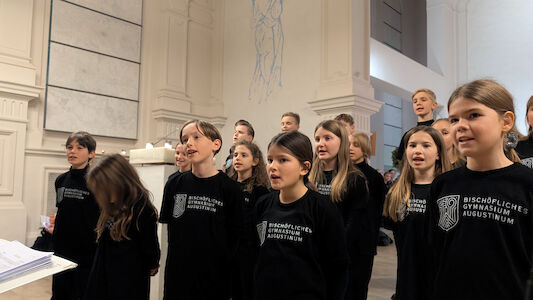 Ein Kinderchor singt in einer Kirche und trägt dazu passende schwarze Pullover.