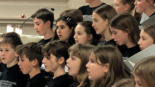 Eine Gruppe von Kindern, die in einem Chor singen und schwarze Hemden tragen.