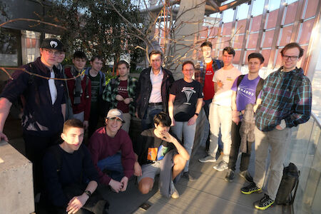 Eine Gruppe Jugendlicher und Erwachsener posiert gemeinsam in einem sonnendurchfluteten Innenraum.