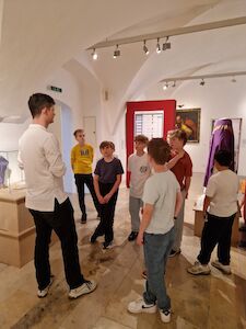 Eine Gruppe von Kindern hört einem Führer in einer Galerie eines Kunstmuseums zu.