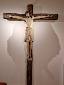 Hölzernes Kruzifix von Jesus Christus an einer Wand mit dramatischen Schattenwürfen.